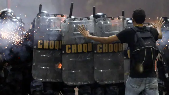 ريو دي جانيرو - متظاهر يحاول إيقاف تقدم الشرطة. أفادت تقارير بأن ما يقرب من 800 ألف شخص نزلوا إلى شوارع كبريات المدن البرازيلية الخميس للتظاهر احتجاجا على سياسات الحكومة. (رويترز)