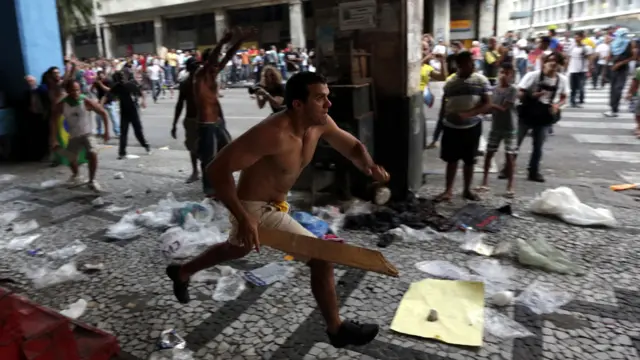 ريسيفي - متظاهر يطارد مخربين حاولوا استغلال المظاهرات لارتكاب أعمال السطو. (رويترز)