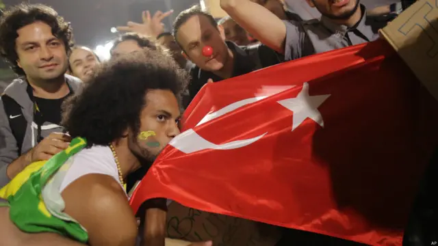 Sao Paulo'daki eylemde bir gösterici Türkiye'deki protestolarla dayanışmayı vurgulamak için Türk bayrağını öptü. 