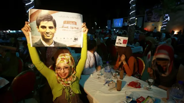 ایک ریسٹورنٹ میں ایک خاتون عساف کا پوسٹر اٹھائے ہوئے۔