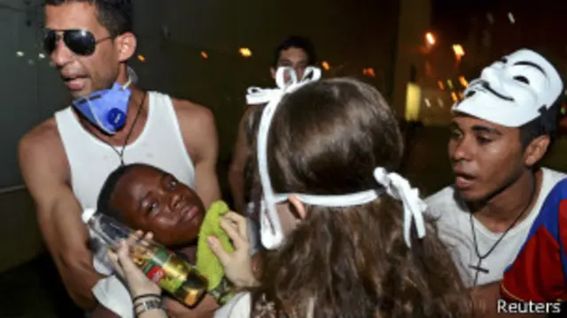 Manifestantes socorrem jovem afetado por gás lacrimogêneo em Salvador (foto: Reuters)