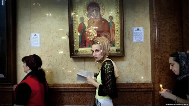 Başı örtüklü gənc qadın Müqəddəs Üçlük Kilsəsində dua oxuyur. Justyna Mielnikiewicz 