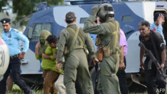 Римша Масих в окружении полицейских