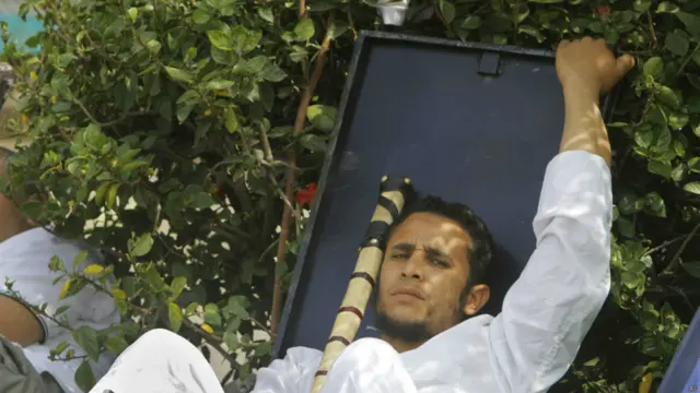 穆爾西的一名支持者手持棍棒，頭枕盾牌，在Rabia el-Adawiya清真寺外的營地休息。