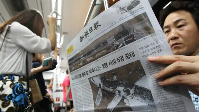 Warga Korea Selatan membaca koran yang memberitakan tentang kecelakaan pesawat Asiana di San Fransisco