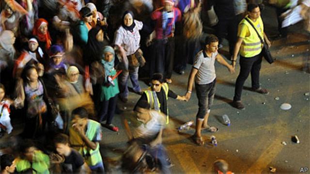 Voluntários tentam proteger mulheres em protesto na praça Tahrir (AP)