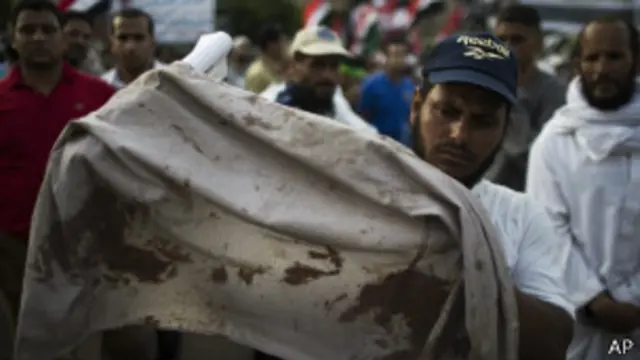 नस्र शहर के पास एक प्रदर्शन में एक मुर्सी समर्थक खून से रंगी कमीज़ दिखाता हुआ