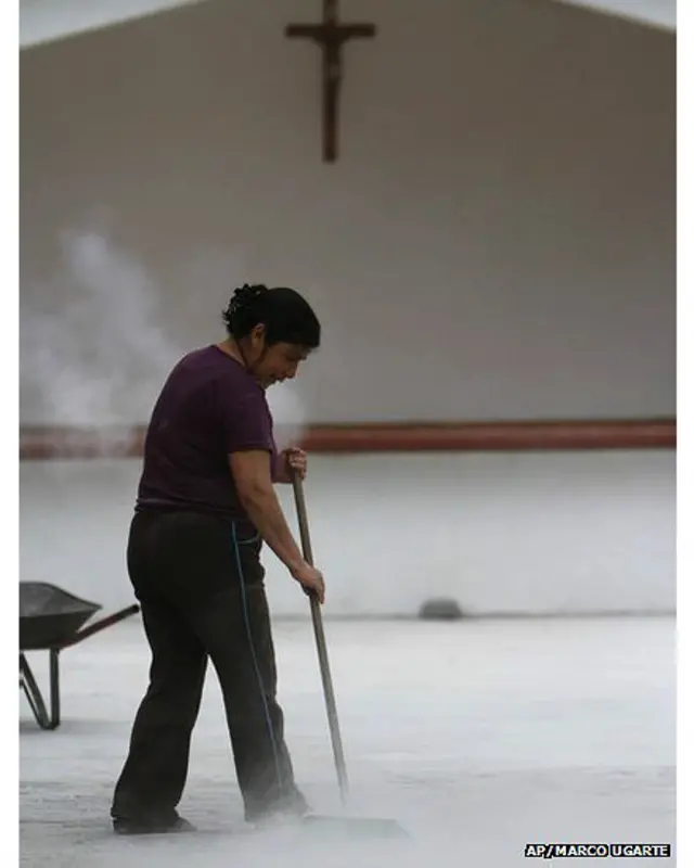 ज्वालामुखी की राख को साफ़ करती एक कर्मचारी.