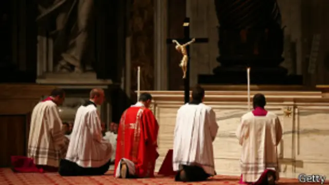 Rohaniwan dan pastor berdoa di hadapan salib, Getty