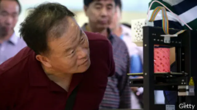 Китаец наблюдает за работой 3D-принтера