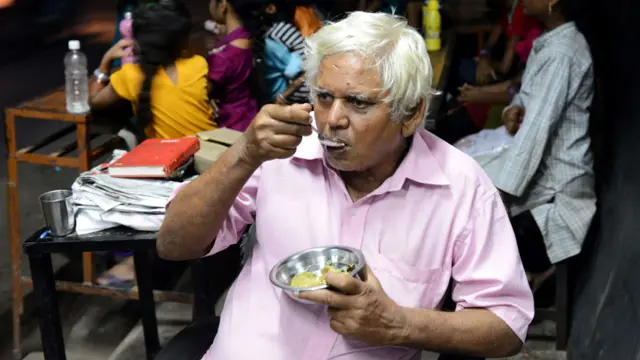 أحمدآباد - الاستاذ كمالبهاي بارمار يتذوق الطعام قبل توزيعه على التلاميذ.