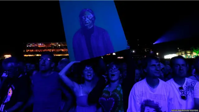 स्विट्ज़रलैंड में चल रहे पालियो संगीत समारोह में कनाडा के संगीतकार नील यंग के कार्यक्रम के दौरान दर्शक उनकी तस्वीर थामे हुए.