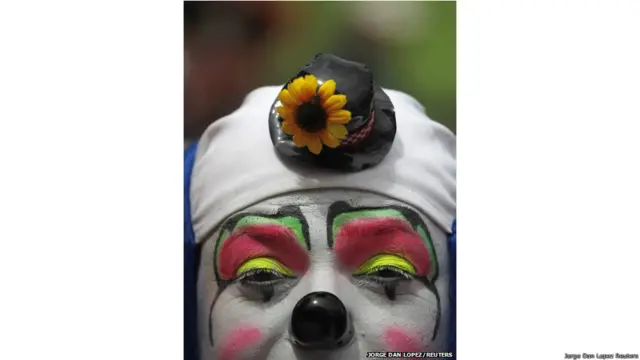 ग्वाटेमाला शहर में आयोजित पांचवे क्लाउन सम्मेलन की उदघाटन परेड के दौरान तस्वीर खिंचवाता एक जोकर