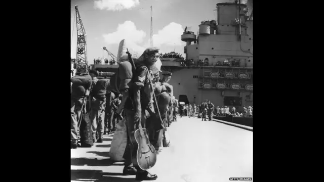 हांगकांग के कोलून के हॉल्ट्स व्हार्फ में मिडलसेक्स रेजिमेंट की पहली बटालियन के सैनिक एचएमएस यूनिकॉर्न में सवार होने का इंतज़ार कर रहे हैं. अगस्त 1950. गेटी इमेजेस 