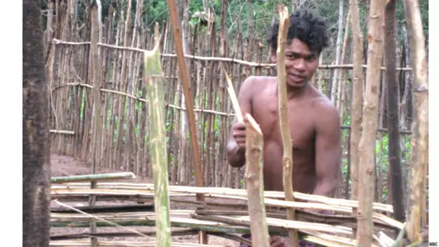 अपनी झोपड़ी के पीछे बांस का बना घेर लगाता एक आदिवासी. 