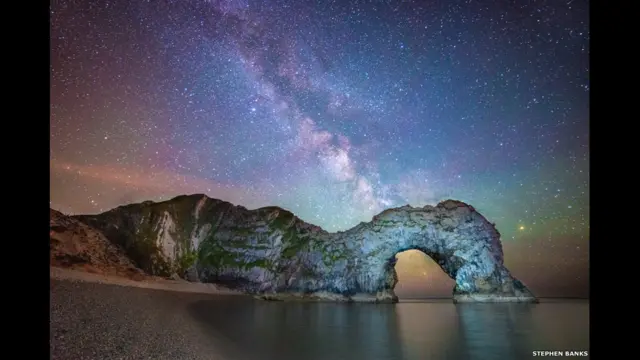 نئے فوٹوگرافروں کے لیے مختص انعام کا نام سکائی ایٹ نائٹ میگزین کے سر پیٹرک مور کے نام پر رکھا گیا ہے۔ اس منتخبہ تصویر میں برطانیہ میں واقع قدرتی محراب ’ڈرڈل گیٹ‘ پیش منظر میں ہے جب کہ اس کے پیچھے آسمان پر ملکی وے کہکشاں پھیلی ہوئی نظر آ رہی ہے۔ 