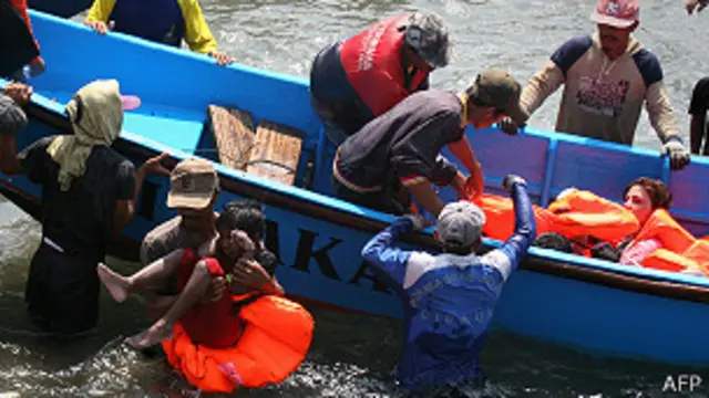 انڈونیشیا کے ساحل پر غیر قانونی طریقے سے کشتی پر پہنچنے والے افراد کی ریسکیو والے مدد کر رہے ہیں