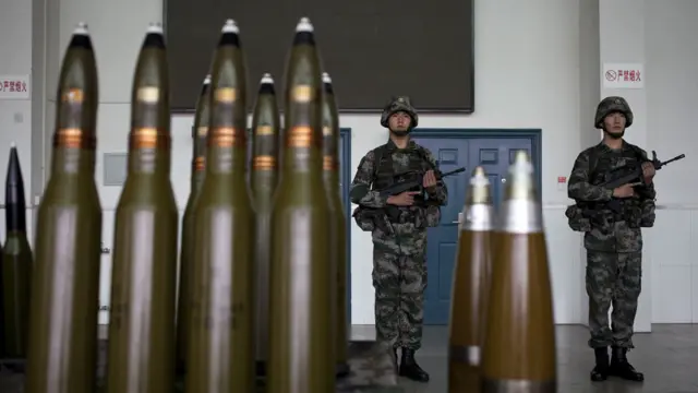 兰州军区的士兵在西安的基地的防空炮弹附近守卫。