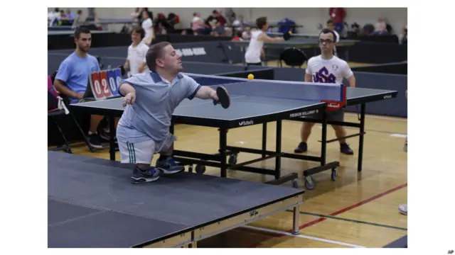 अमरीका की मिशिगन स्टेट यूनिवर्सिटी में तीन से 10 अगस्त तक 2013 वर्ल्ड ड्वार्फ़ गेम्स का आयोजन हुआ. बौनों की इस वैश्विक खेल प्रतियोगिता में एडी केन्ना एक प्लेटफॉर्म पर खड़े होकर टेबल टेनिस प्रतिस्पर्धा में अपने प्रतियोगी रॉजर पॉउलियट का मुकाबला करते हुए.