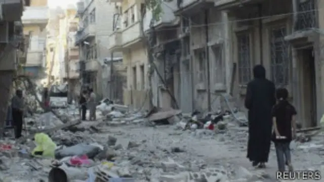 Pessoas caminham pela devastada cidade de Homs