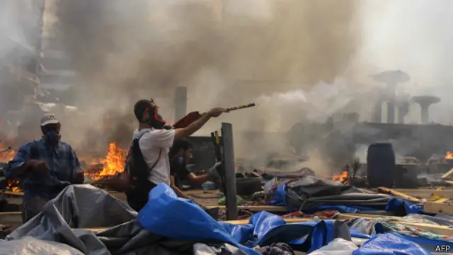 Simpatizante da Irmandade Muçulmana dispara fogo de artifício em direção à polícia, em meio a confrontos no Cairo (AFP)