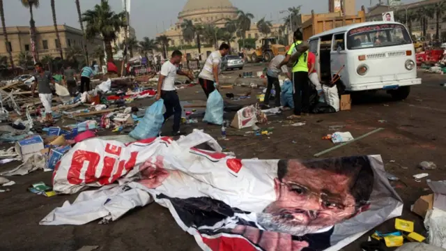 قاہرہ کے نہدا سکوائر میں کارروائی کے بعد لوگ بچا ہوا سامان اٹھاتے ہوئے۔