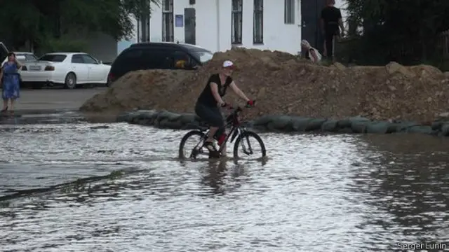 Женщина едет на велосипеде по затопленной улице в Благовещенске