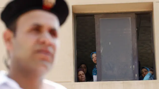 قاہرہ میں بدھ کو ہلاک ہونے والے ایک پولیس اہلار کے جنازے کے موقع پر چند سرکاری ملازم کھڑکی سے جھانک رہی ہیں