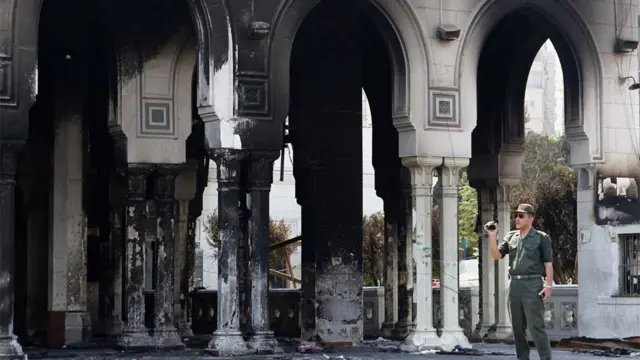 ایک مصری فوجی اہلکار مسجد رابعہ العدویہ کی تصویر لے رہا ہے۔ اس مسجد سے مظاہرین کو پرتشدد مظاہرے کے بعد نکالا گیا تھا۔