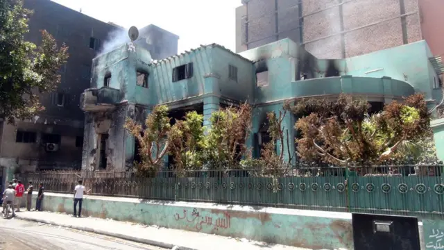 ایک عیسائی خیراتی ادارے کی عمارت سے دھواں اٹھتا ہوا نظر آ رہا ہے۔ شدت پسندوں نے حکومت کے ساتھ ساز باز کے الزام میں اس عمارت کو نذرِ آتش کر دیا تھا۔