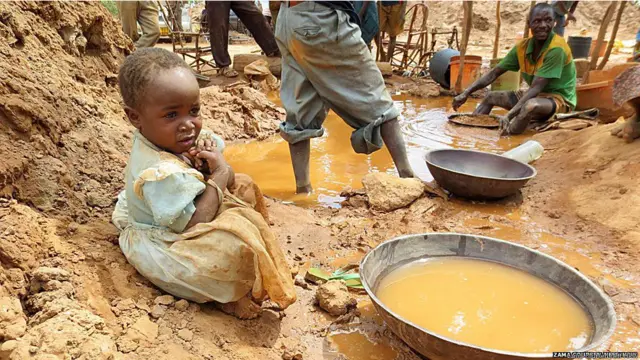 सोना खदानों में काम कर रहे बच्चों को पारे से होने वाले ज़हरीले प्रभाव का ख़तरा. काम ना करने वाले बच्चे भी अक्सर इन जगहों पर मौजूद होते हैं जैसे ये चार साल की बच्ची एक पारा युक्त तालाब के पास बैठी है.