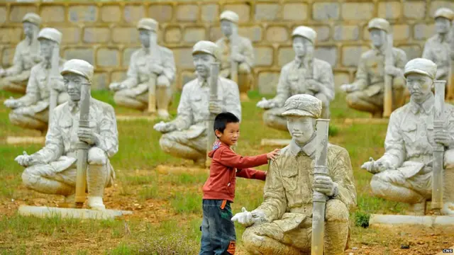 雲南龍陵松山戰役雕塑群內一名小孩觸摸其中一座雕塑（中新社圖片3/9/2013）