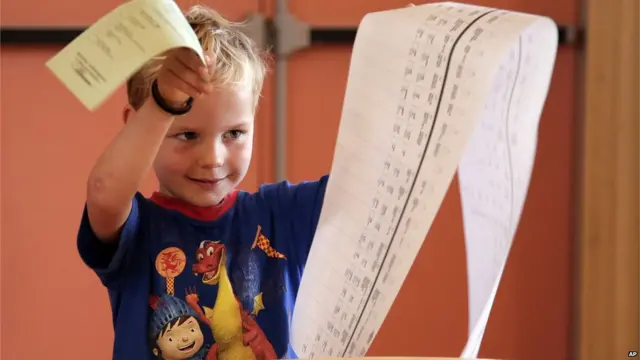 悉尼某投票站內一名小男孩給父母拿著選票（7/9/2013）