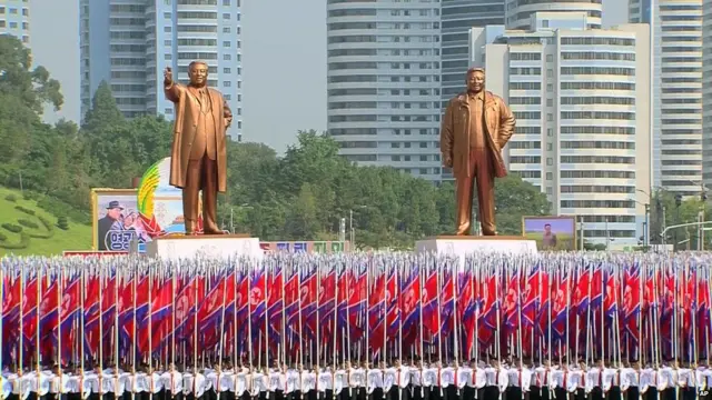 朝鮮國旗方陣與已故領導人金日成（左）、金正日（右）的巨型塑像通過金日成廣場（9/9/2013）