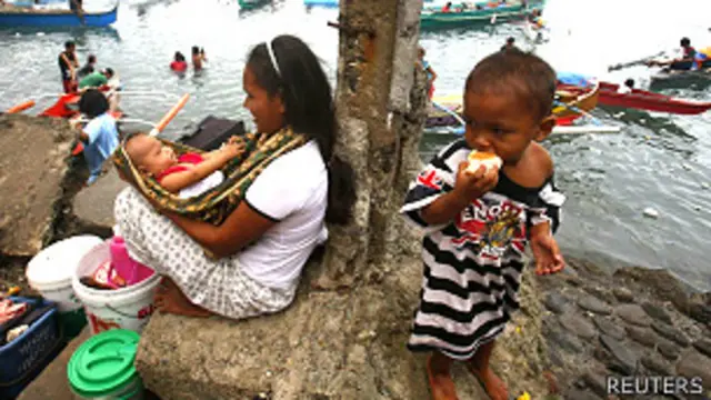 Una mujer desplazada con un bebé y un niño en Filipinas