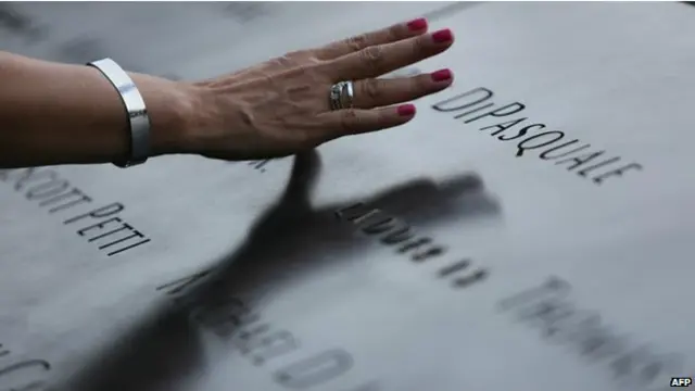 न्यूयार्क में 9/11 के मृतकों के नाम वाली मेटल प्लेट को स्पर्श करते हुए एक महिला.