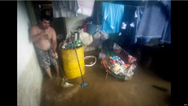 Un hombre trata de achicar el agua de su hogar en Acapulco 