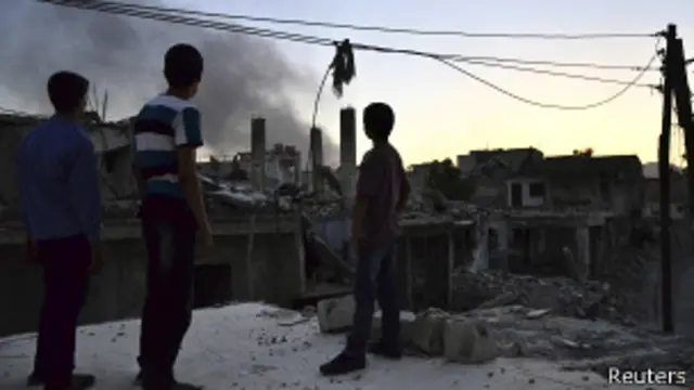 Crianças observam fumaça de suposto tanque do governo destruído por rebeldes