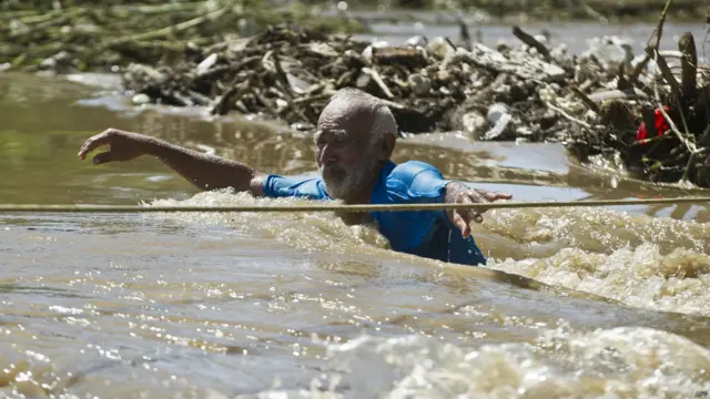 Un hombre intenta cruzar una calle inundada en Acapulco