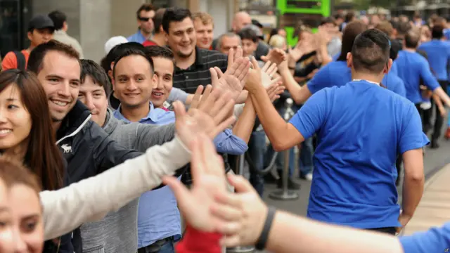 استقبال کارکنان آبی‌پوش فروشگاه اپل در گلیندیل، کالیفرنا از مشتریانی که برای خرید آی‌فون جدید صف کشیده‌اند، برخی از علاقمندان آی‌فون بیش از 10 شب را در صف سپری کرده‌اند