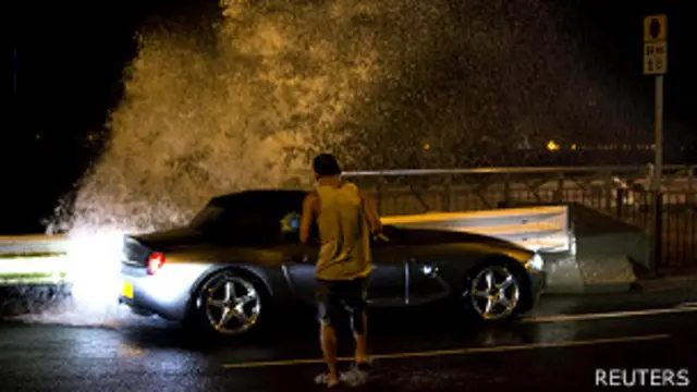 رجل يحاول العودة إلى سيارته بينما خلال الاعصار في هونغ كونغ