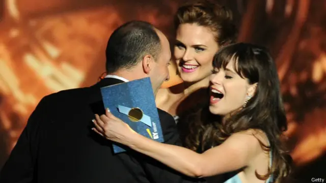 تونی هال در حال دریافت جایزه‌اش از امیلی دشانل و زویی دشانل در مراسم اهدا شصت و پنجمین دوره جوایز امی در لس آنجلس