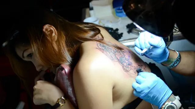 Festivalde bir kadın dövme yaptırıyor. Festivale Asya ülkeleri ve ABD'den birçok dövme sanatçısı katıldı.