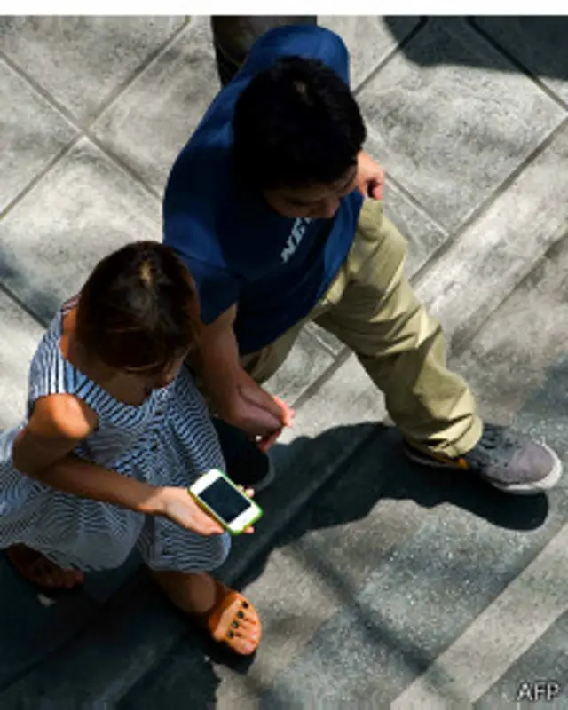 Persona camina mientras ve su teléfono inteligente.