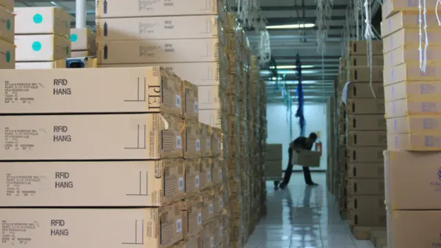 Seorang pekerja menyusun kardus pakaian yang sudah siap di ekspor. Trisula Internasional memiliki dua pabrik garmen lainnya di sekitar Bandung. Selain untuk ekspor, ada beberapa produk yang ditujukan untuk pasar domestik. 