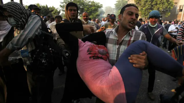 एक घायल महिला को ले जाता एक व्यक्ति