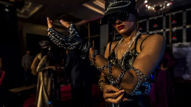 ریمپ پر جانے سے پہلے ایک ماڈل اپنے لباس سے جڑی زنجیریں درست کر رہی ہیں۔