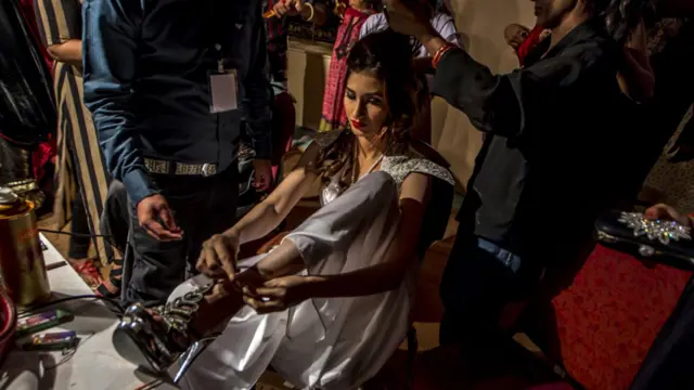 ریمپ پر جانے سے پہلے کے چند لمحات جہاں ایک جانب ماڈل اپنے جوتے پہن رہی ہیں، اور ڈیزائنرز ان کے بالوں اور میک اپ کو دیکھ ہے ہیں۔