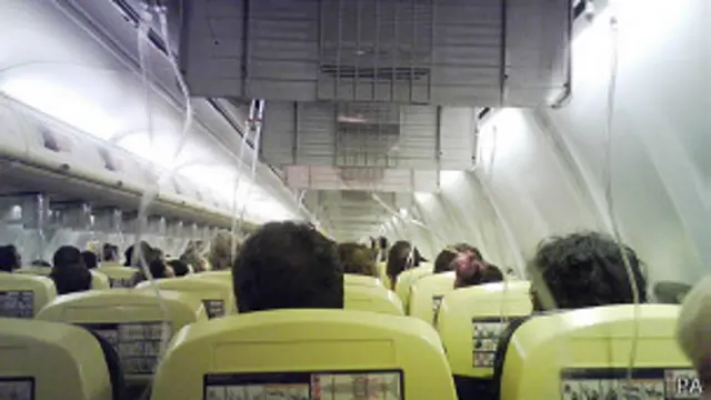 Una cabina de avión con las máscaras de oxígeno afuera