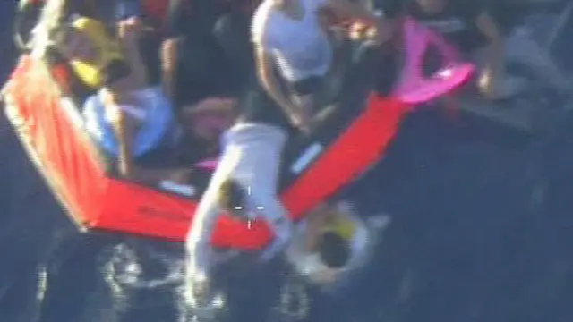 Foto yang diambil dari tayangan televisi memperlihatkan tim penyelamat menolong korban.